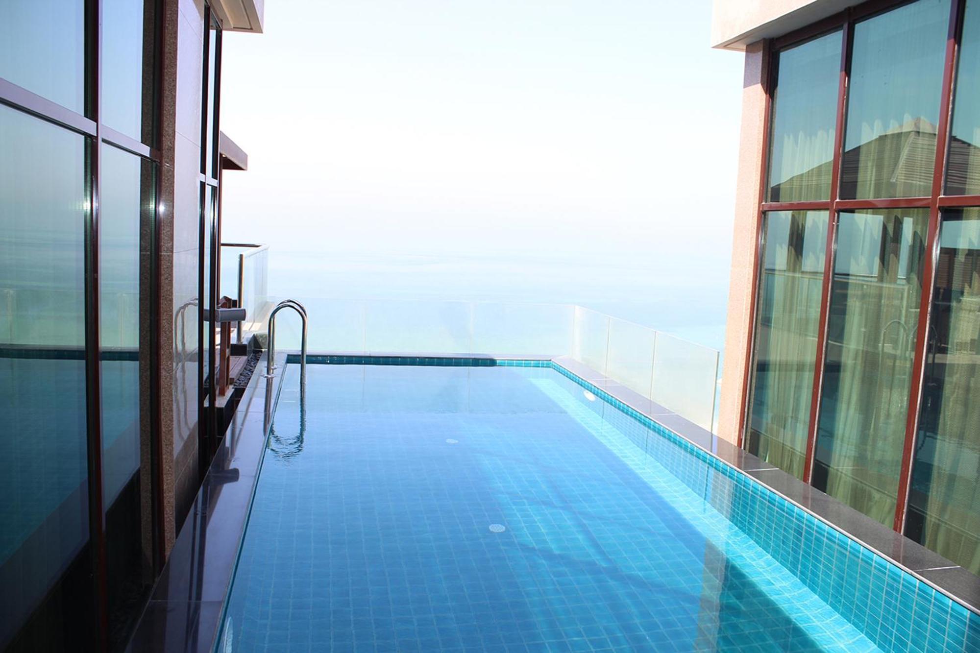 泻湖畔豪华spa度假村 麦纳麦 外观 照片 The photo shows an infinity pool situated on a balcony or rooftop, with a clear view extending to the horizon. The pool has a sleek design with blue tiles, and it appears to be reflecting the sky. There is a ladder on one side for access into the poo