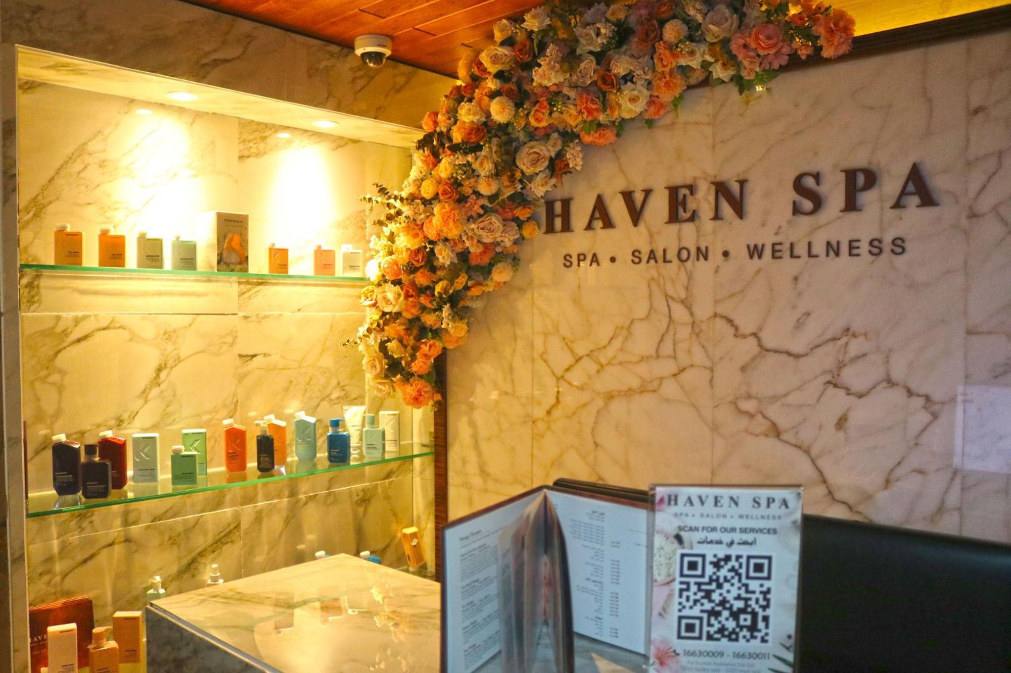 泻湖畔豪华spa度假村 麦纳麦 外观 照片 The photo shows the interior of a spa called "Haven Spa." The wall is decorated with beautiful artificial flowers, creating an inviting atmosphere. There are several shelves displaying various colorful bottles and products, likely for skincare or wel