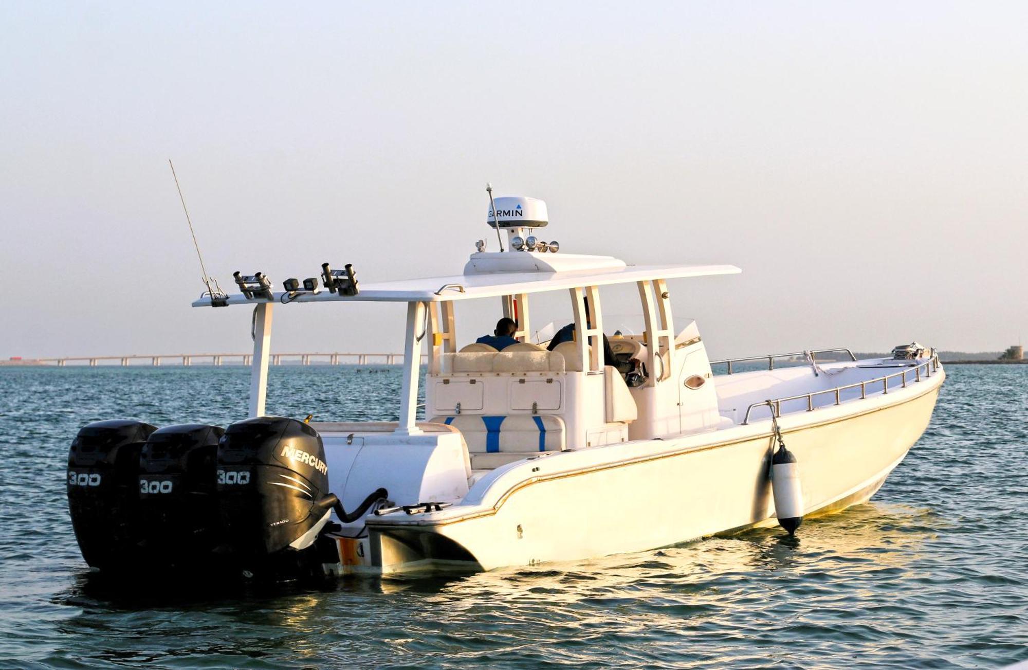 泻湖畔豪华spa度假村 麦纳麦 外观 照片 The photo shows a large, white motorboat equipped with three powerful outboard engines at the stern. The boat has a sleek design, with a spacious open deck and a covered cabin area that likely provides shelter and controls for navigation. The scene i