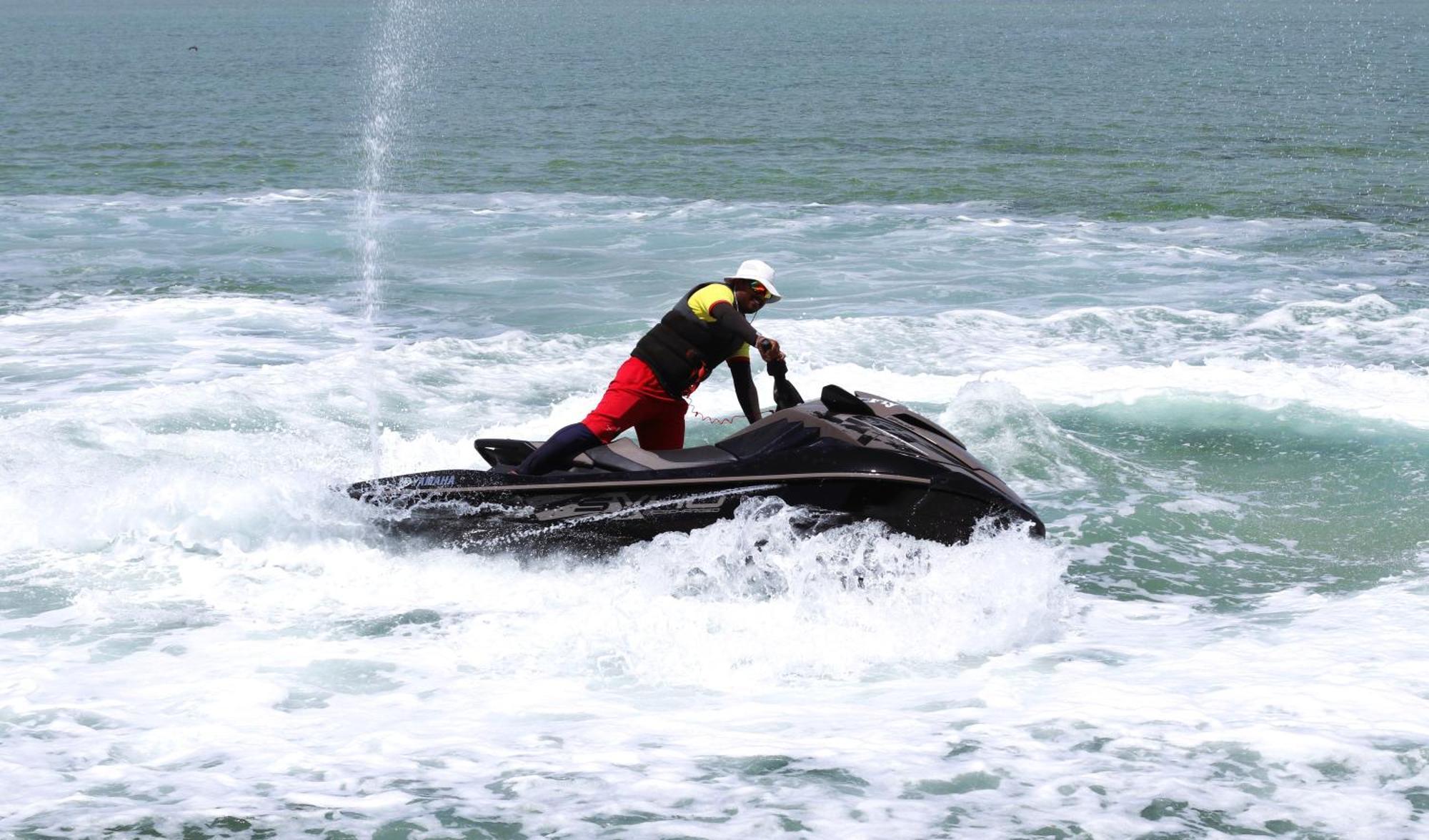 泻湖畔豪华spa度假村 麦纳麦 外观 照片 The photo shows a person riding a jet ski on the water. The rider is positioned upright, leaning forward with one hand on the handlebars, while the jet ski creates splashes of white foam around it. The water appears choppy, likely due to the motion o