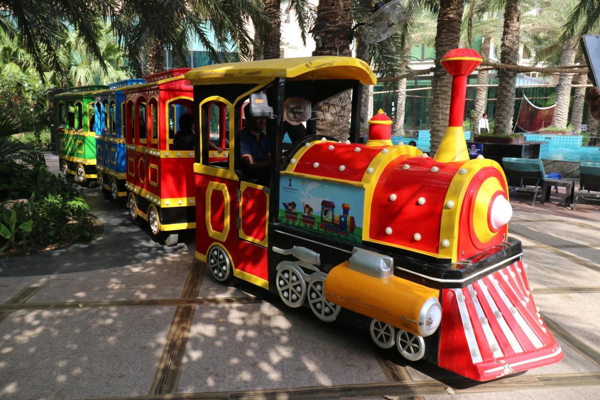 泻湖畔豪华spa度假村 麦纳麦 外观 照片 The photo shows a colorful miniature train. It features a vibrant design with bright red, yellow, and blue colors. The front of the train resembles a classic steam engine, complete with a prominent smokestack. The train is designed to resemble a fun 