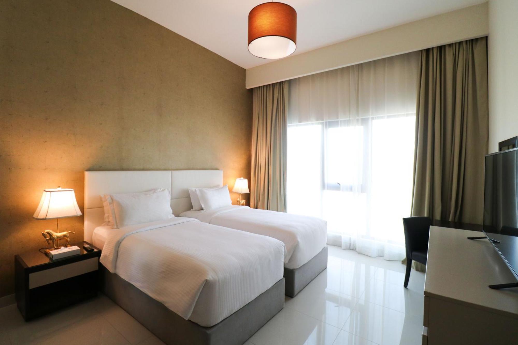 泻湖畔豪华spa度假村 麦纳麦 外观 照片 The photo shows a hotel room featuring two single beds with white bedding. The walls have a neutral tone, and there's a large window covered by light, sheer curtains allowing natural light to enter. On either side of the beds, there are bedside table